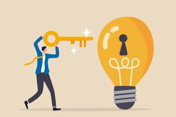 man holding gold key and putting it into light bulb with key hole