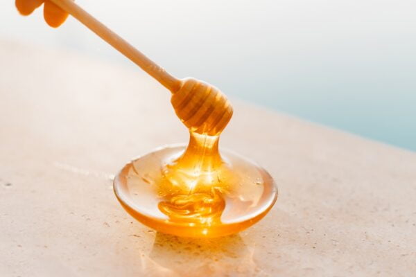 honey being dripped into small bowl using stick