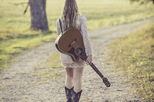 lady holding a guitar in park