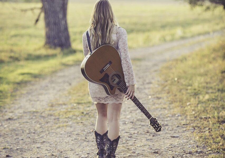 lady holding a guitar in park