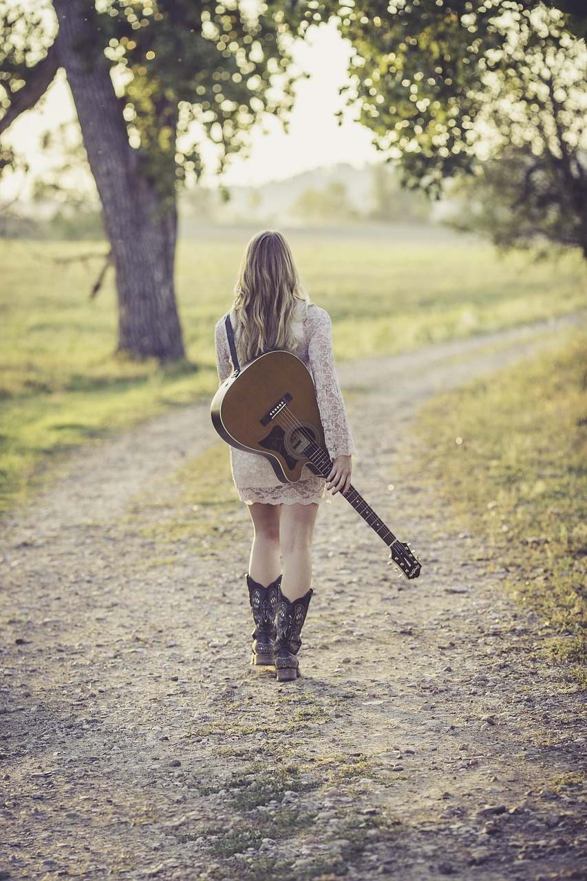 lady holding a guitar in park
